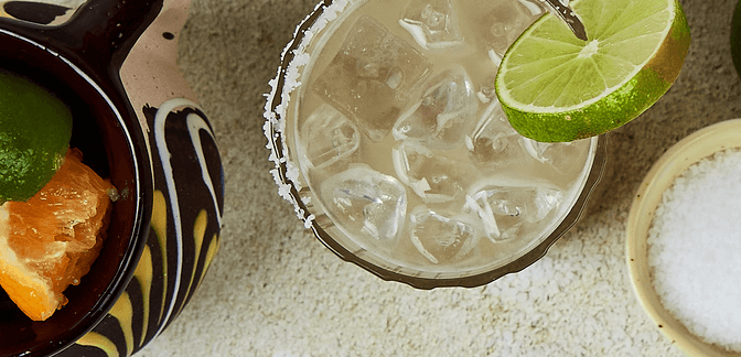 A selection of fresh fruit, salt, and a cold margarita.